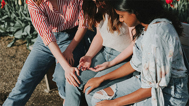 Three women sitting and praying together