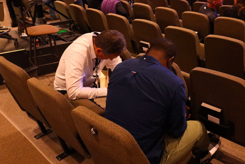 Two men pray together.