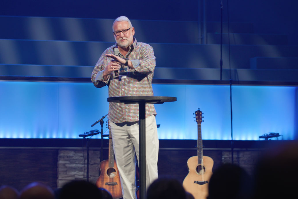 Pastor speaks to an audience from the stage.