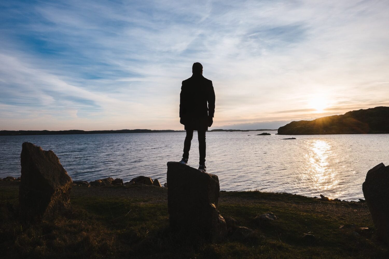 silouhette of a man standing by a lake